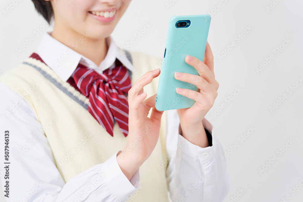 白背景でスマホをタップする女子高生の手元