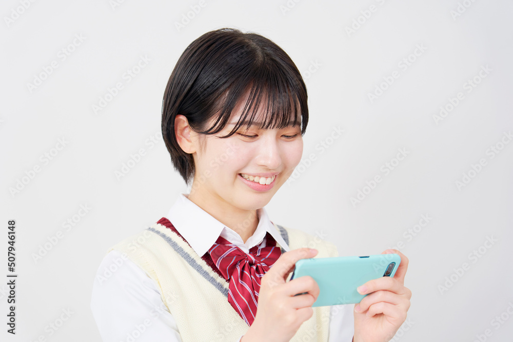 白背景でスマホで動画を見る女子高生