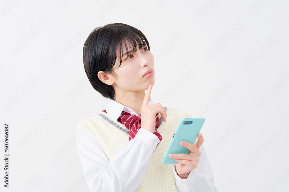 白背景でスマホを持って考える女子高生