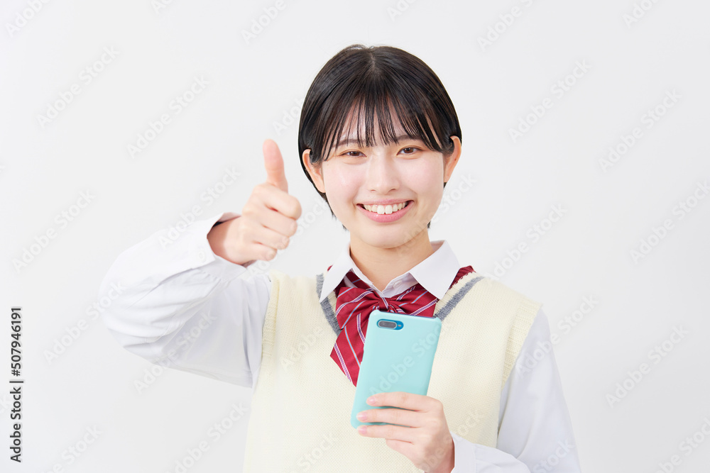 白背景でスマホを持ってグッドサインする女子高生