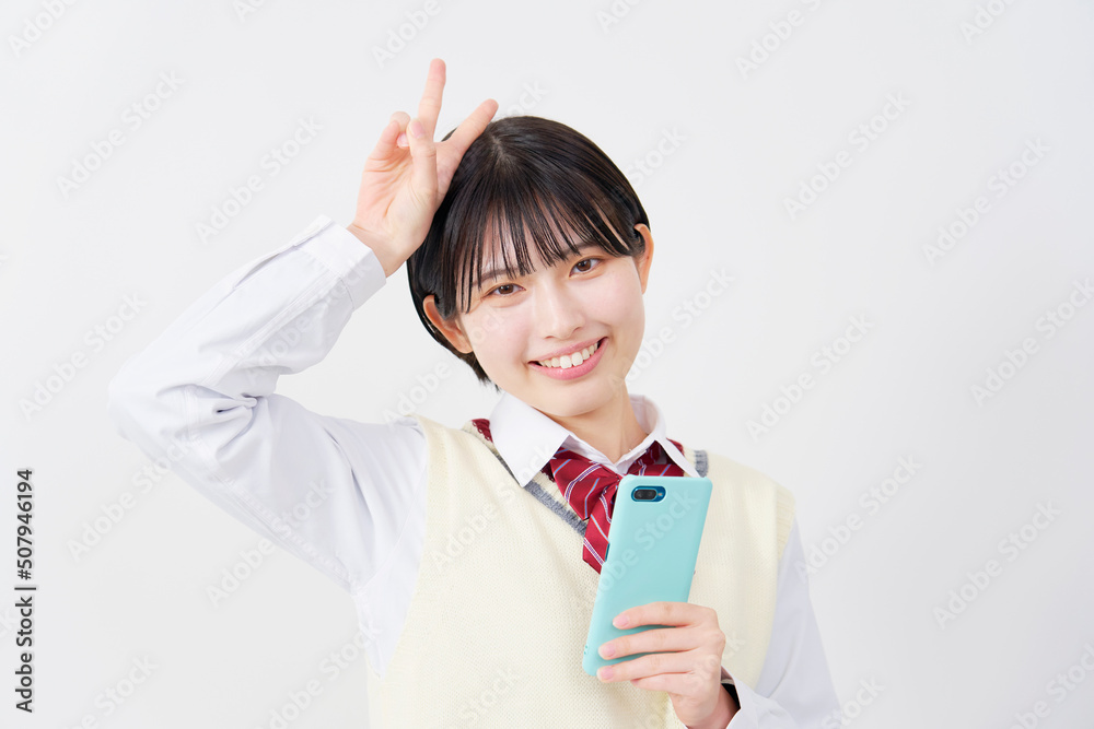 白背景でスマホを持ってピースサインする女子高生