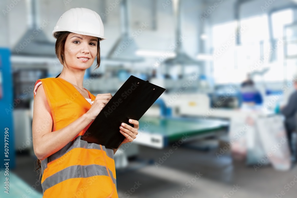 Studio portrait of lady or female engineer wearing a safety helmet and a reflective jacket