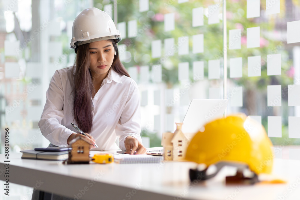 女建筑设计师在笔记本电脑上工作，在办公室写建筑项目。