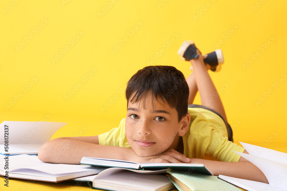 Little boy with open books on yellow background