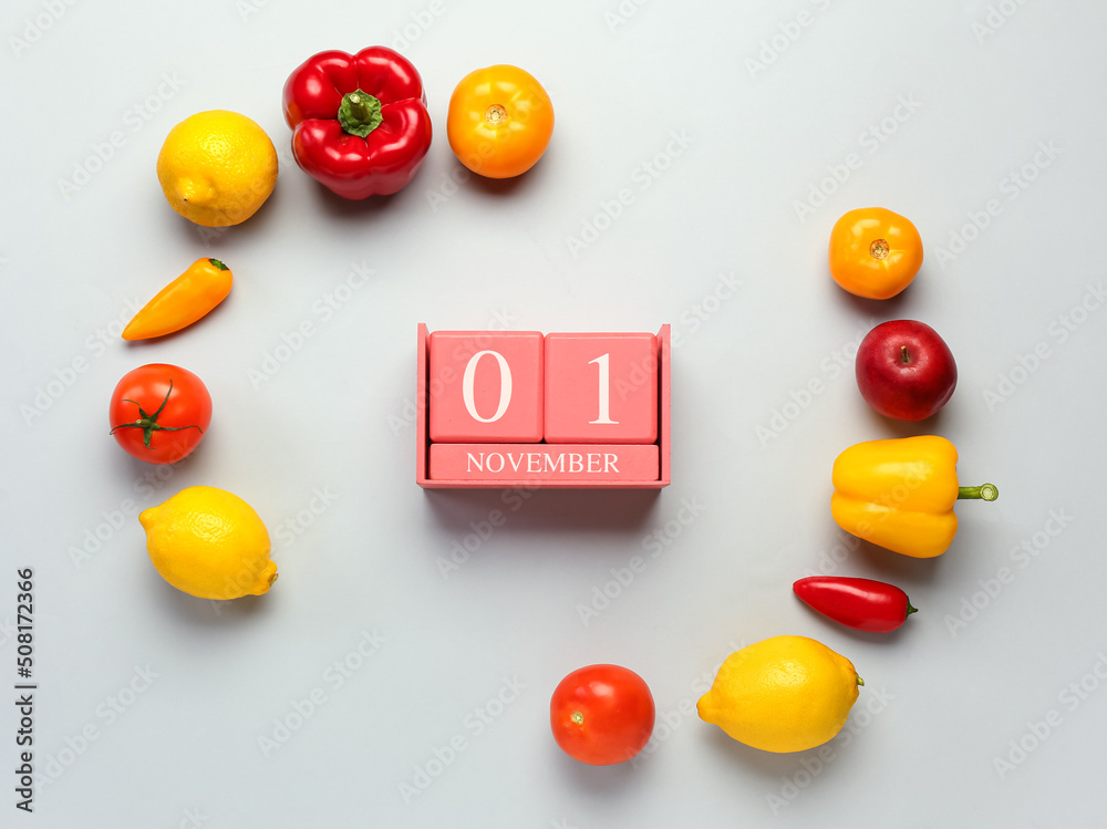 Fresh fruits, vegetables and cube calendar with date NOVEMBER 1 on grey background. World Vegan Day 