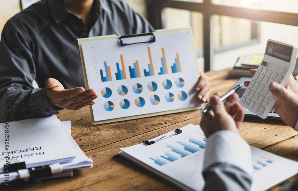 Businessman holding business marketing financial report presenting it to colleagues on a desk at a m