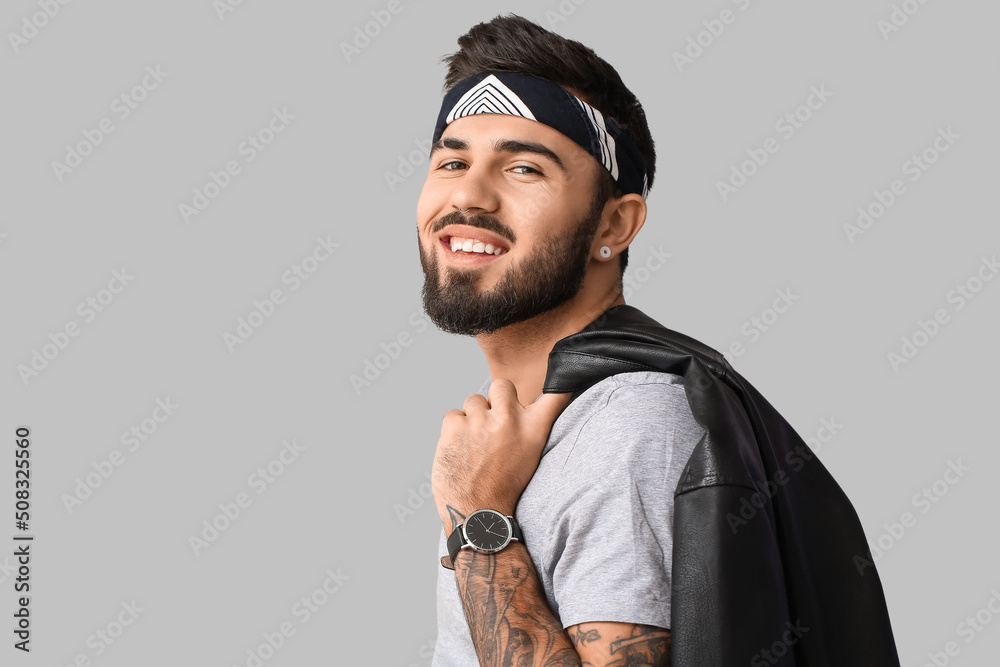 Smiling bearded man holding jacket over shoulder on light background