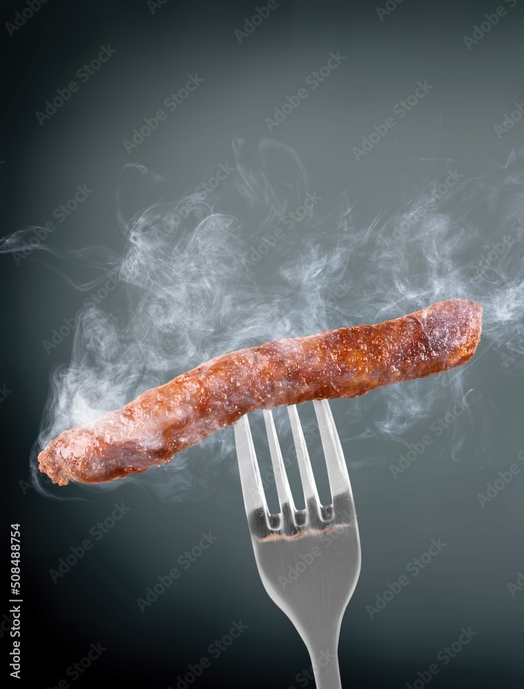 Big fried hot thinking sausages on a fork. Grilled sausage concept.