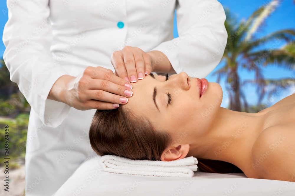 Beauty and relaxation concept - beautiful young woman on massage at spa over tropical beach backgrou