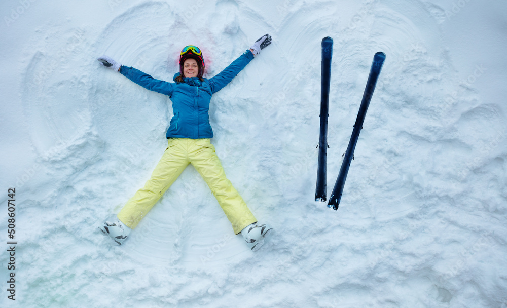 Skier woman wear sport coat helmet and mask lay in snow with ski