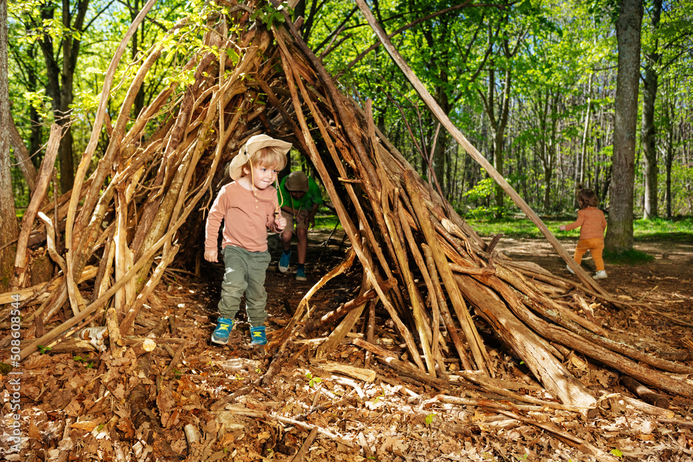 Boy with boy-scout hat plain in the forest hut of branches