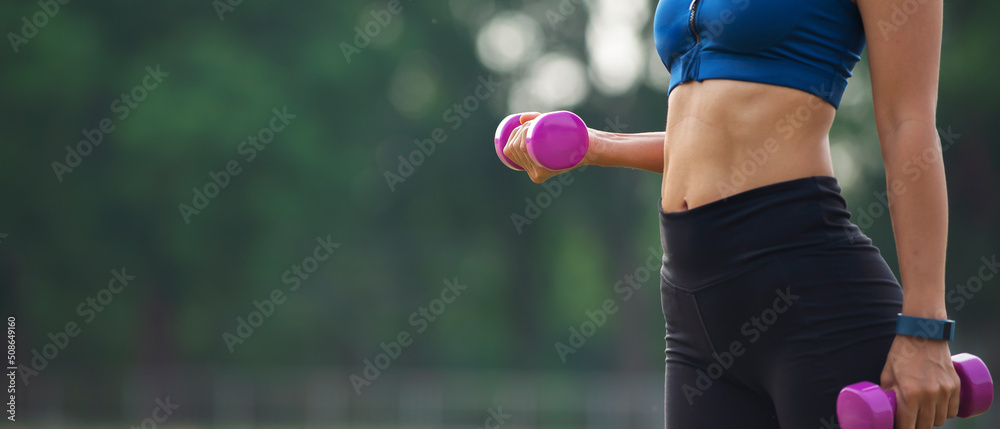 Asian woman in sport clothes  with smart watch on hands workout with dumbbell at park