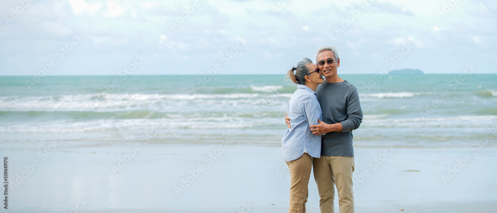 亚洲老年夫妇在海滩上散步，享受日出的生活