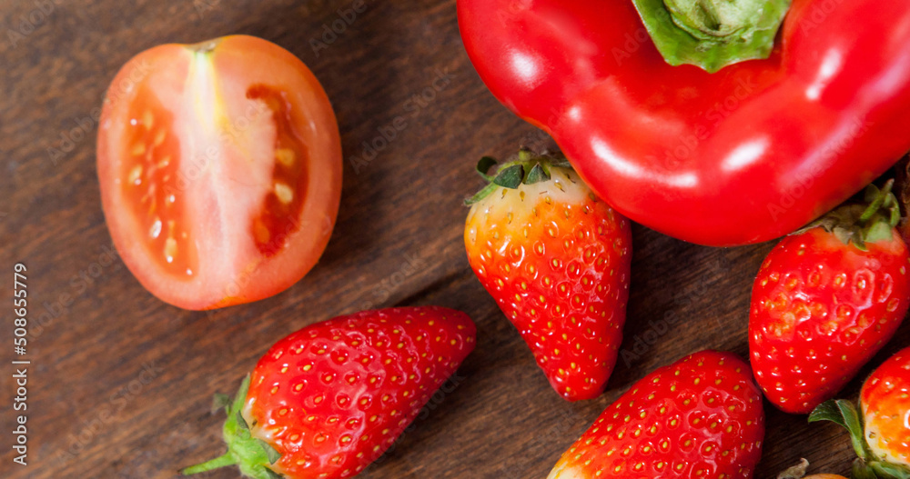 Image of fresh organic vegan food with strawberries and red vegetables on wood