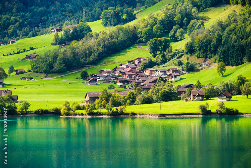 Lungern, canton of Obwalden, Switzerland. A view of rural homes in a green meadow. A lake in a mount