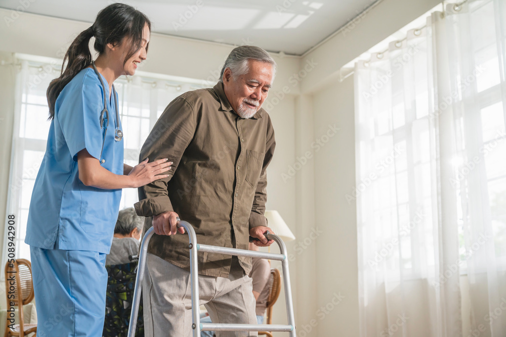 young asian female nurse care giver helping asian senior old man with mobility walker in living area