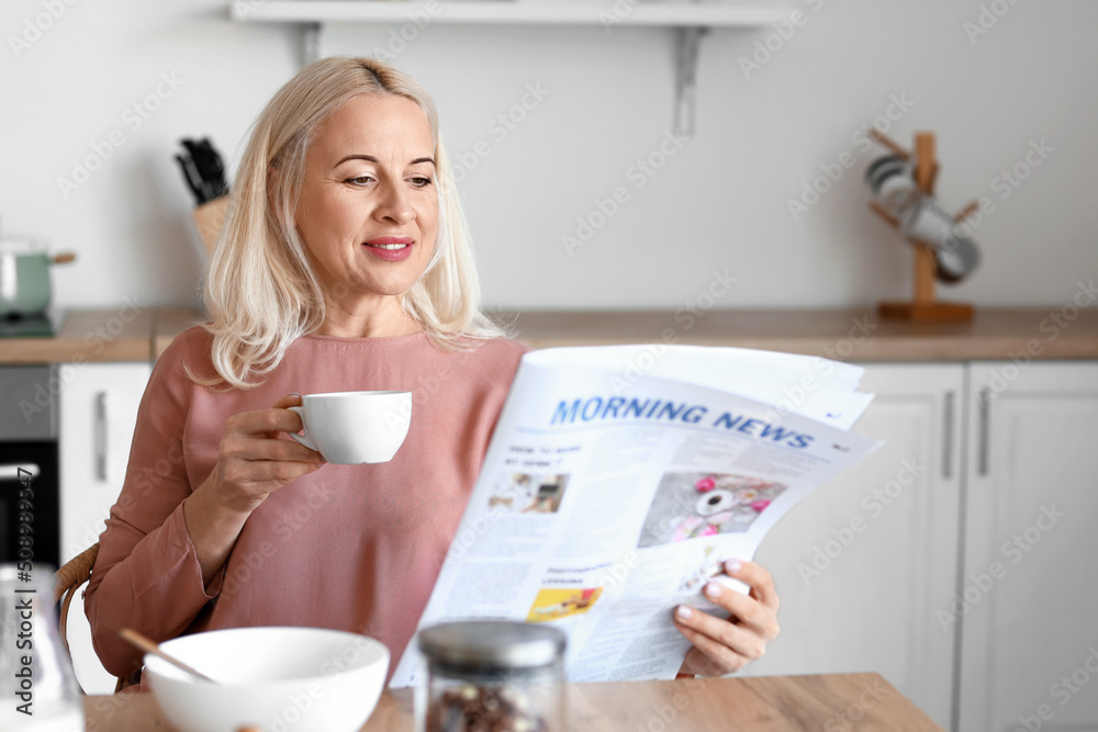 成熟女人在厨房喝咖啡读报的早晨