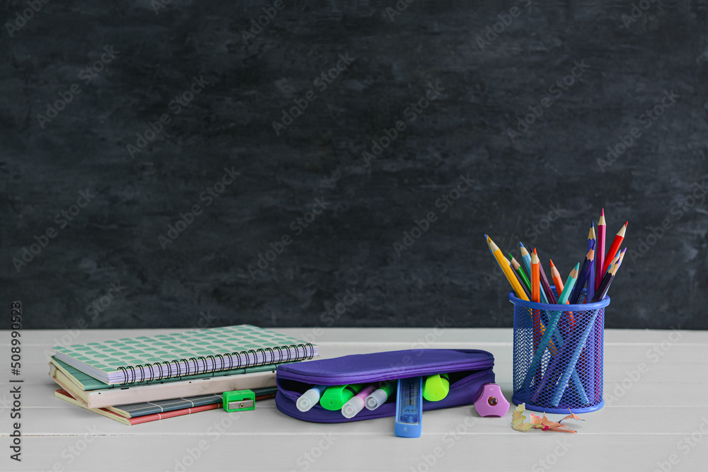 Different stationery on table near black wall