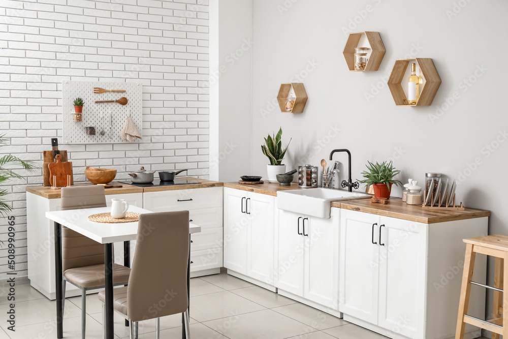 Interior of light kitchen with dining table, counters and utensils