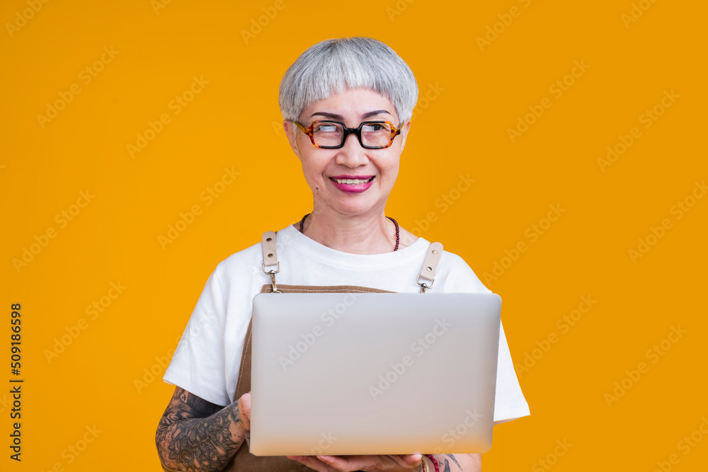 senior old female tattoo business owner wear apron hand hold laptop portrait smile,online marketing 