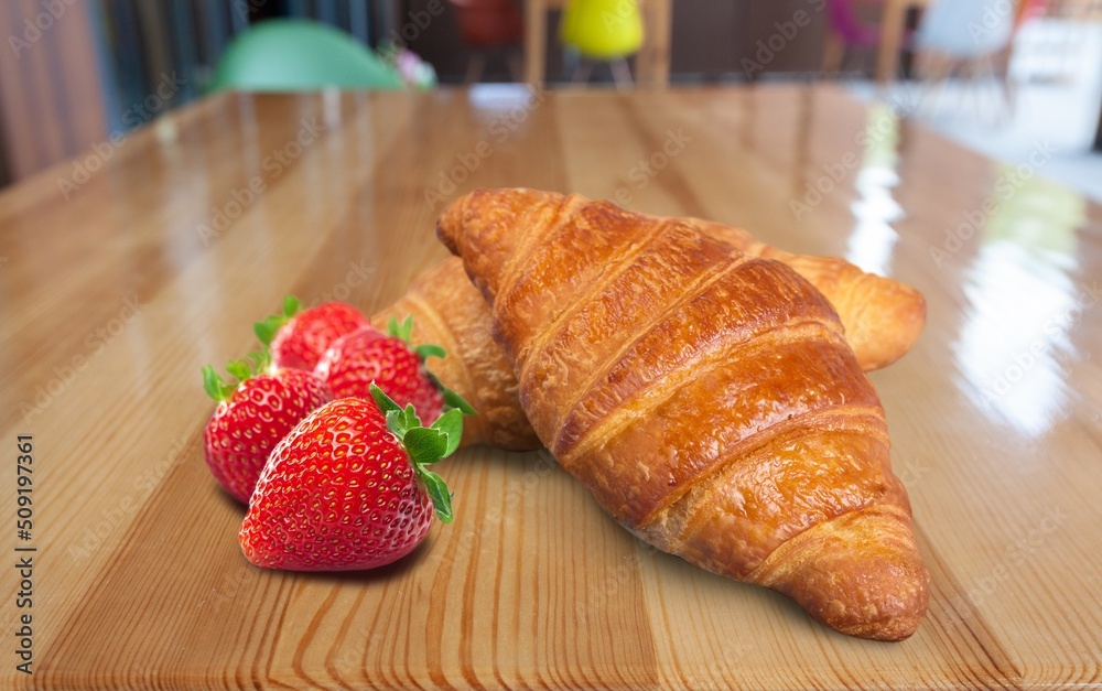 Tasty sweet Croissant with strawberry and cream on the desk