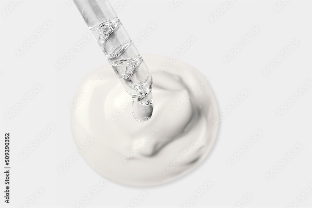 Cosmetic pipette with drops of oil, on the background of white cosmetic cream smear on the desk