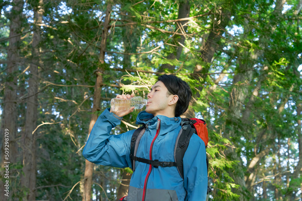 ペットボトルの水を飲む登山中の男性