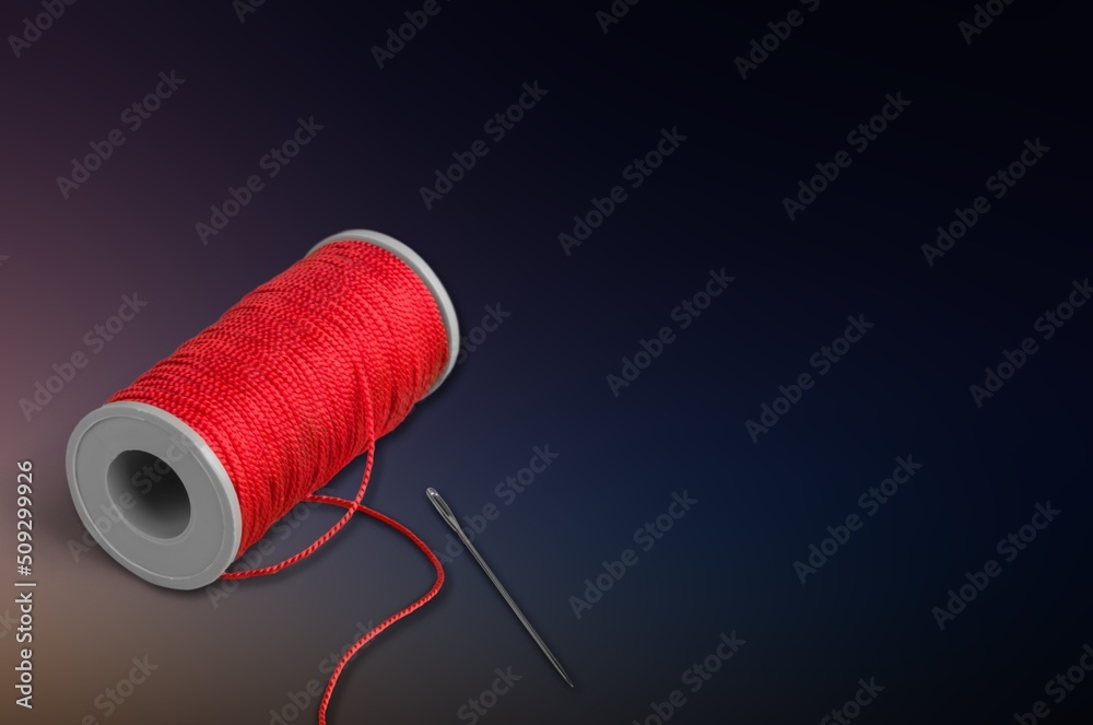 A sewing thread with needle on dark background,