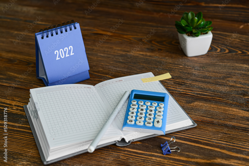 Calendar, notebook, calculator and felt-tip pen on wooden background