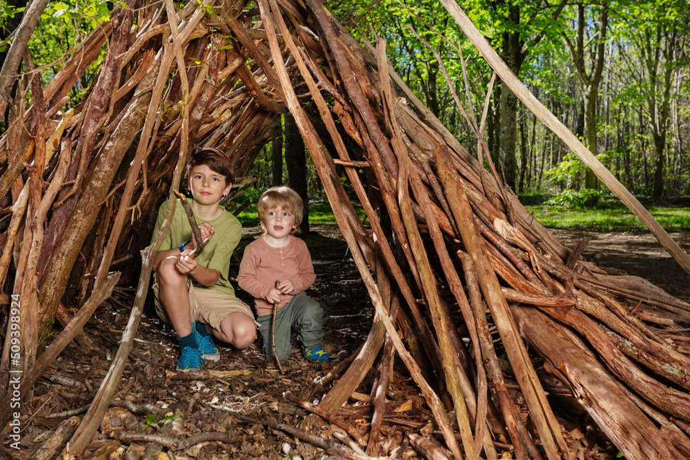 Two boys play build hut of branches in the forest