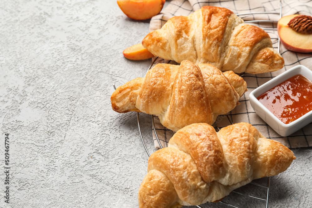 Delicious croissants with peach jam on light background