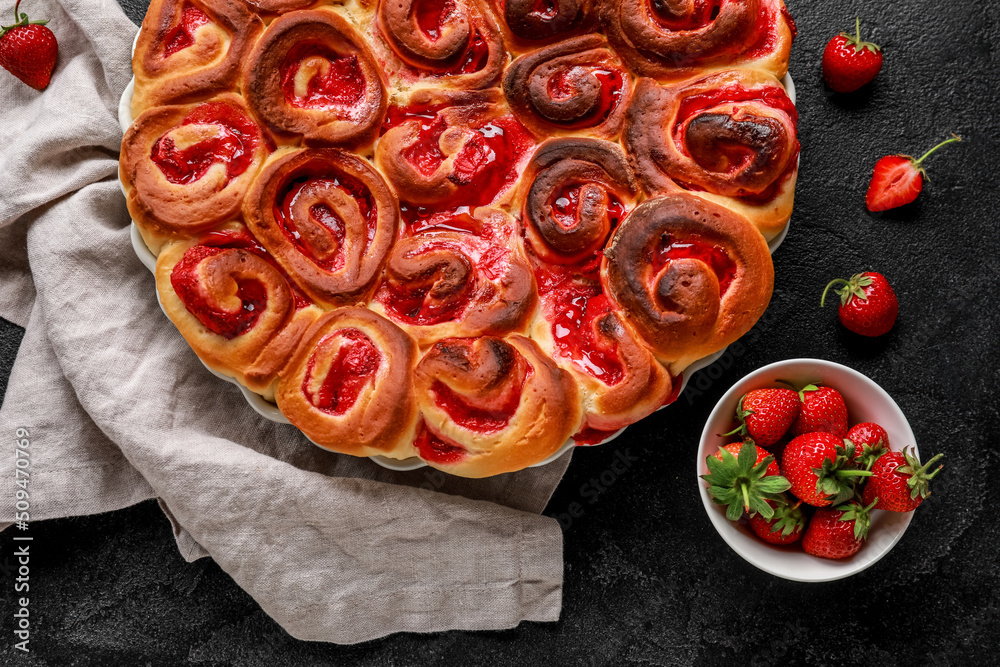 Baking dish with strawberry cinnamon rolls on dark background