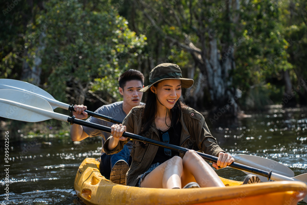 Asian attractive romantic young couple rowing kayak in a forest lake. 