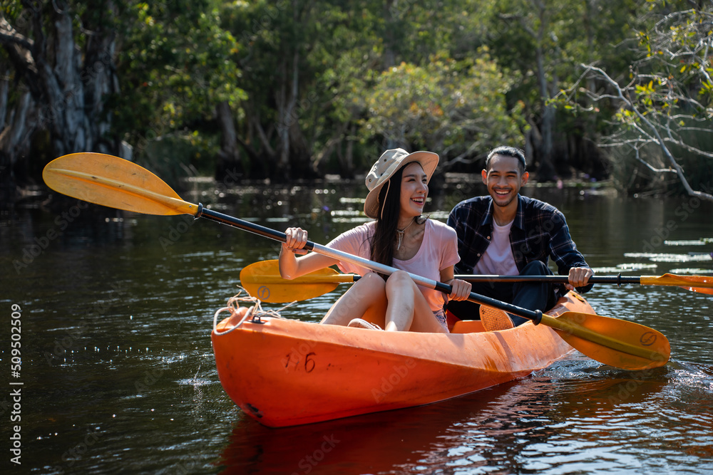 Asian attractive romantic young couple rowing kayak in a forest lake. 