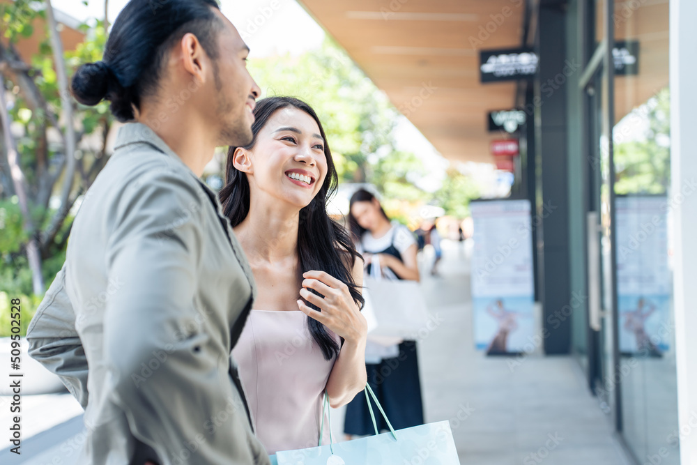 亚洲年轻男女在百货公司户外购物。