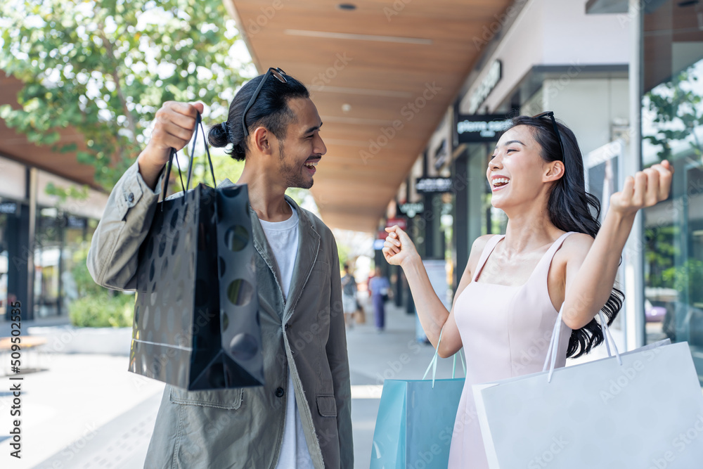 Asian young man and woman shopping goods outdoors in department store. 