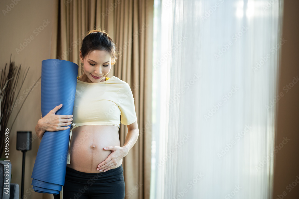 Asian beautiful young woman pregnant in sportswear standing at home.	