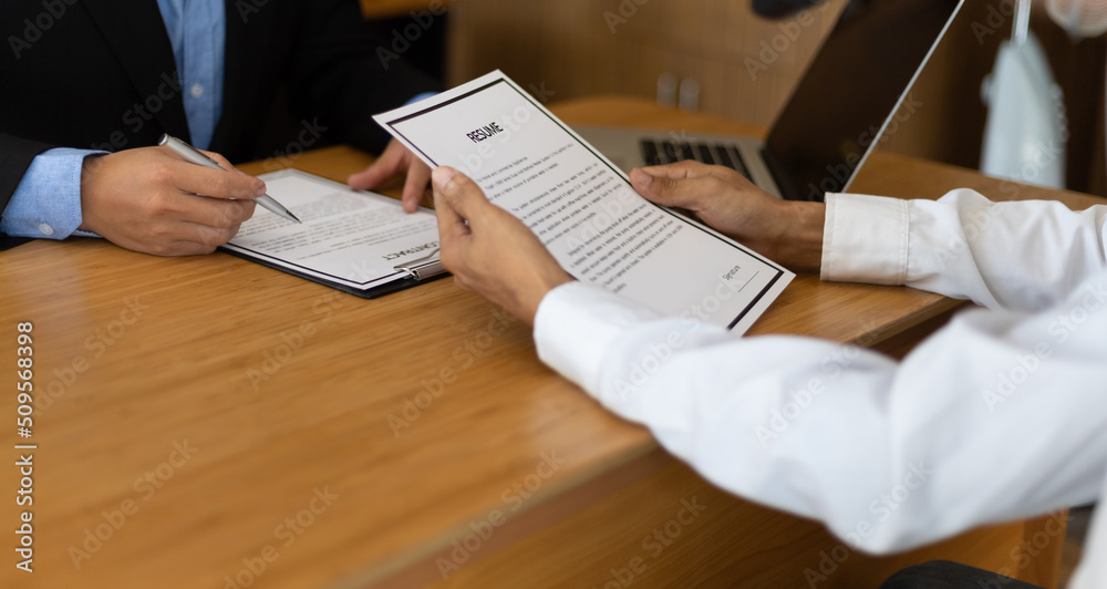 Job applicant holding a resume is discussing and interviewing with a manager in the recruitment offi