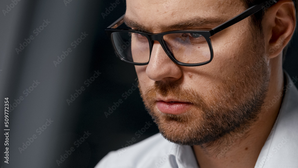 Working young businessman in eyeglasses at a laptop after hours in the evening