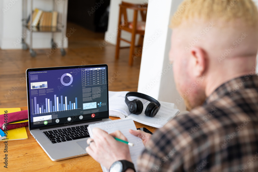 African american albino businessman working on graphs on laptop during video conference