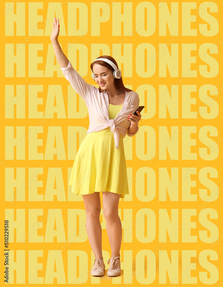 Happy young redhead woman listening to music on yellow background with words HEADPHONES