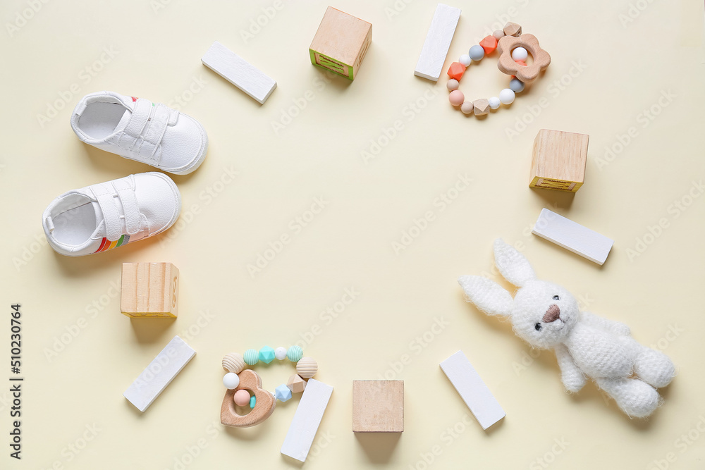 Frame made of children toys and booties on beige background