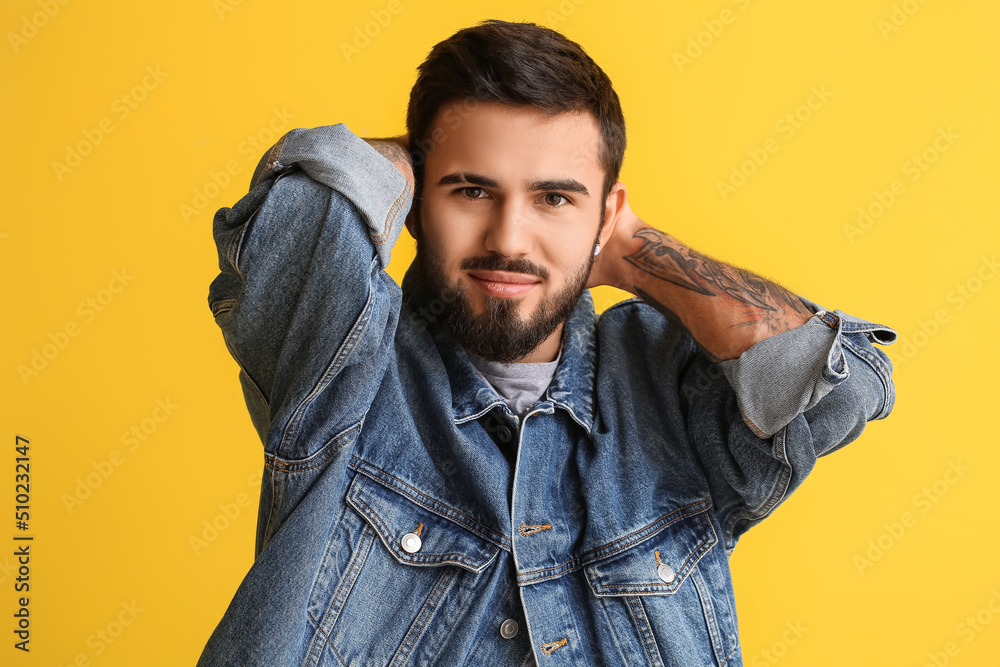 Bearded man keeping hands behind head on yellow background