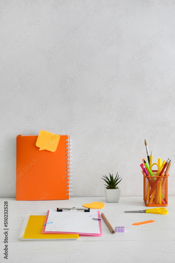 Different stationery on table near light wall