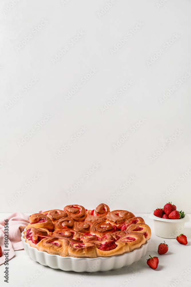 Baking dish with strawberry cinnamon rolls on white background