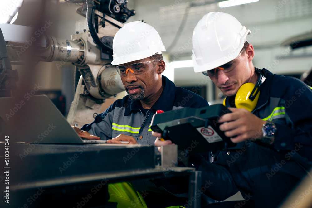 Factory workers working with adept robotic arm in a workshop . Industry robot programming software f