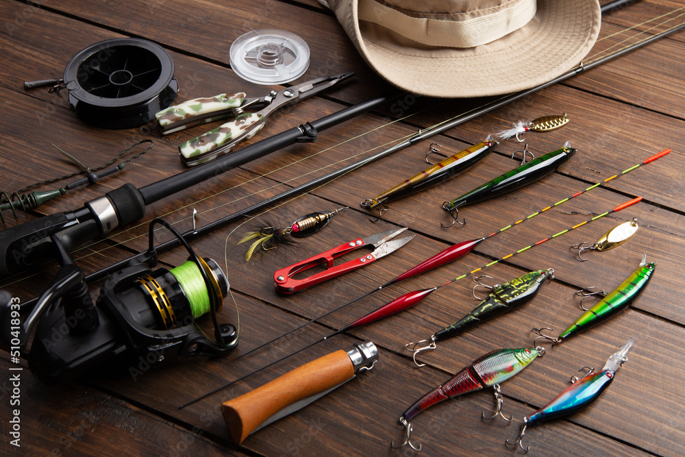 Fishing tackle - fishing spinning rod, hooks and lures on wooden background. Active hobby recreation