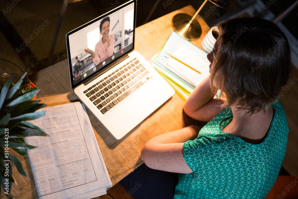 Caucasian businesswoman having online meeting with female coworker while working late in office