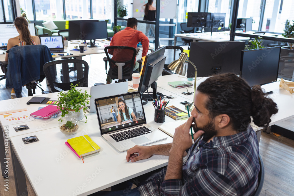 African american businessman video conferencing with female coworker over laptop in office