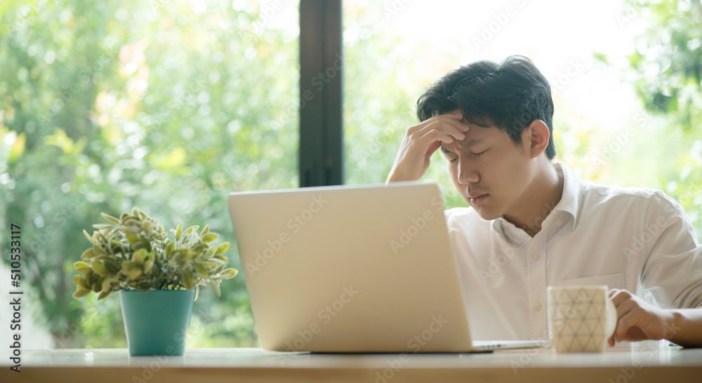 Young Asian man having stressful time working on laptop